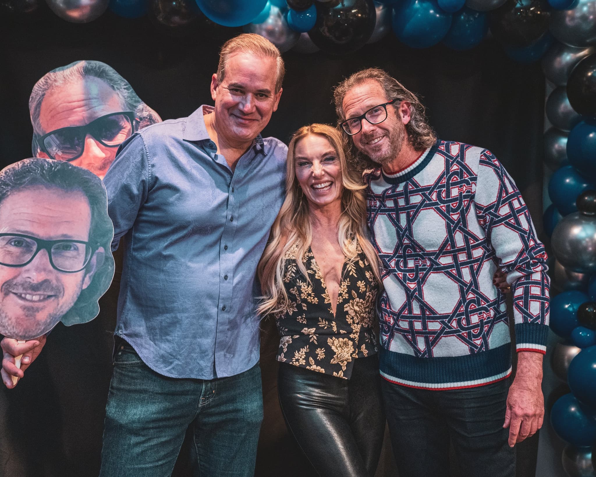 Guests posing with oversized novelty face cutouts at the balloon arch