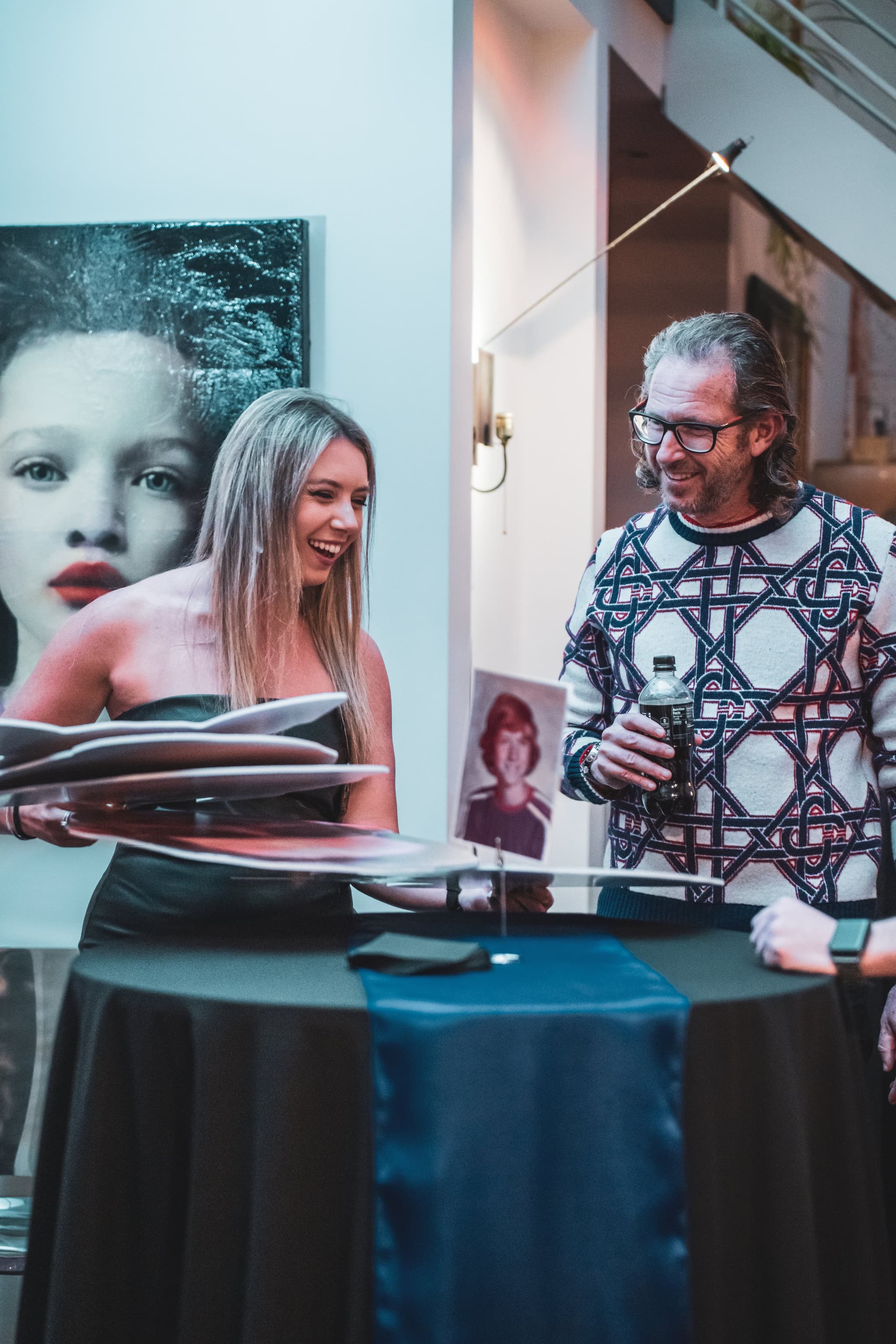 The birthday honoree shares a joyful laugh with a woman as she flips through a photo book at the party