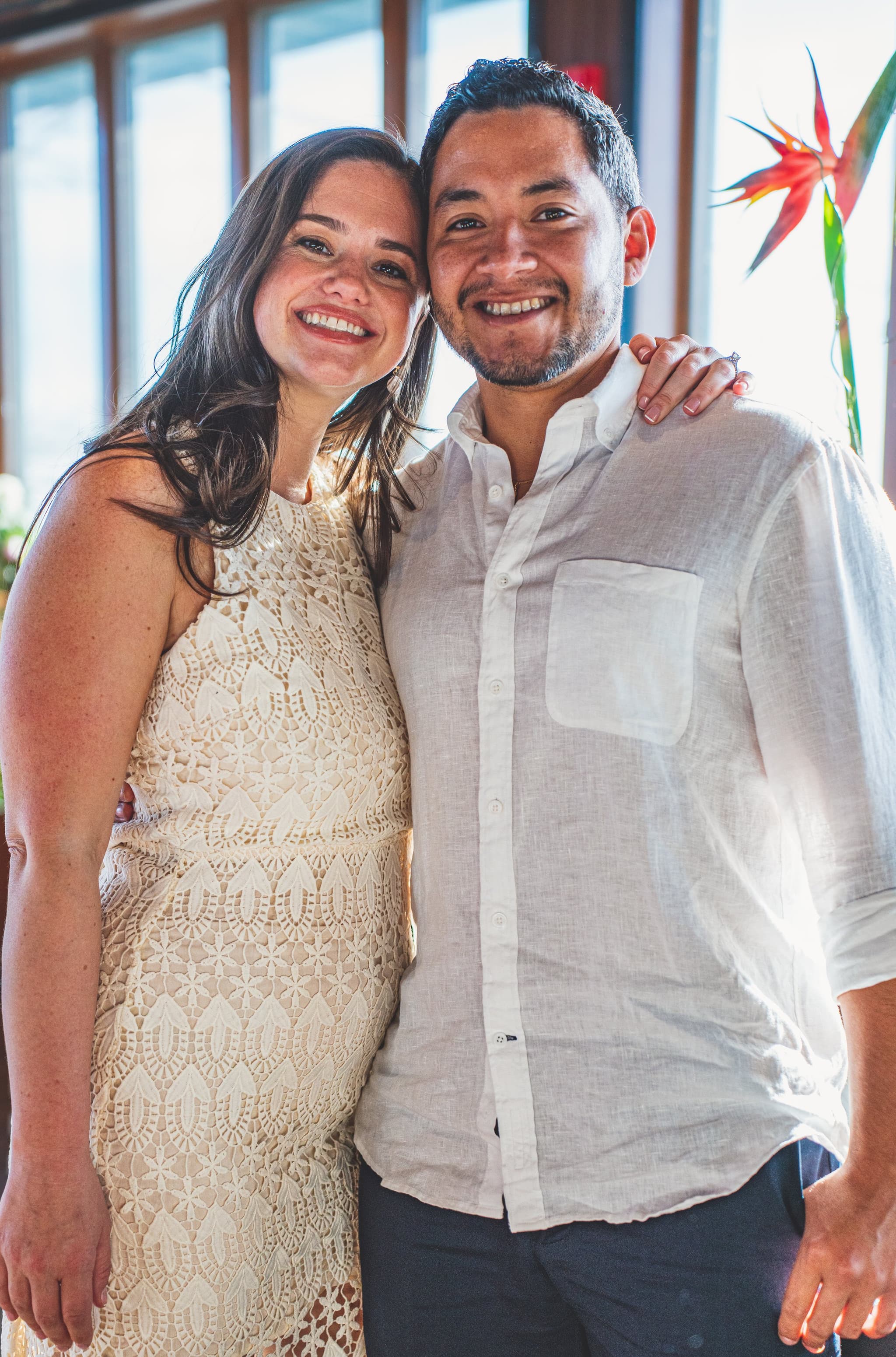 Bride and partner in close portrait with natural window light and floral backdrop