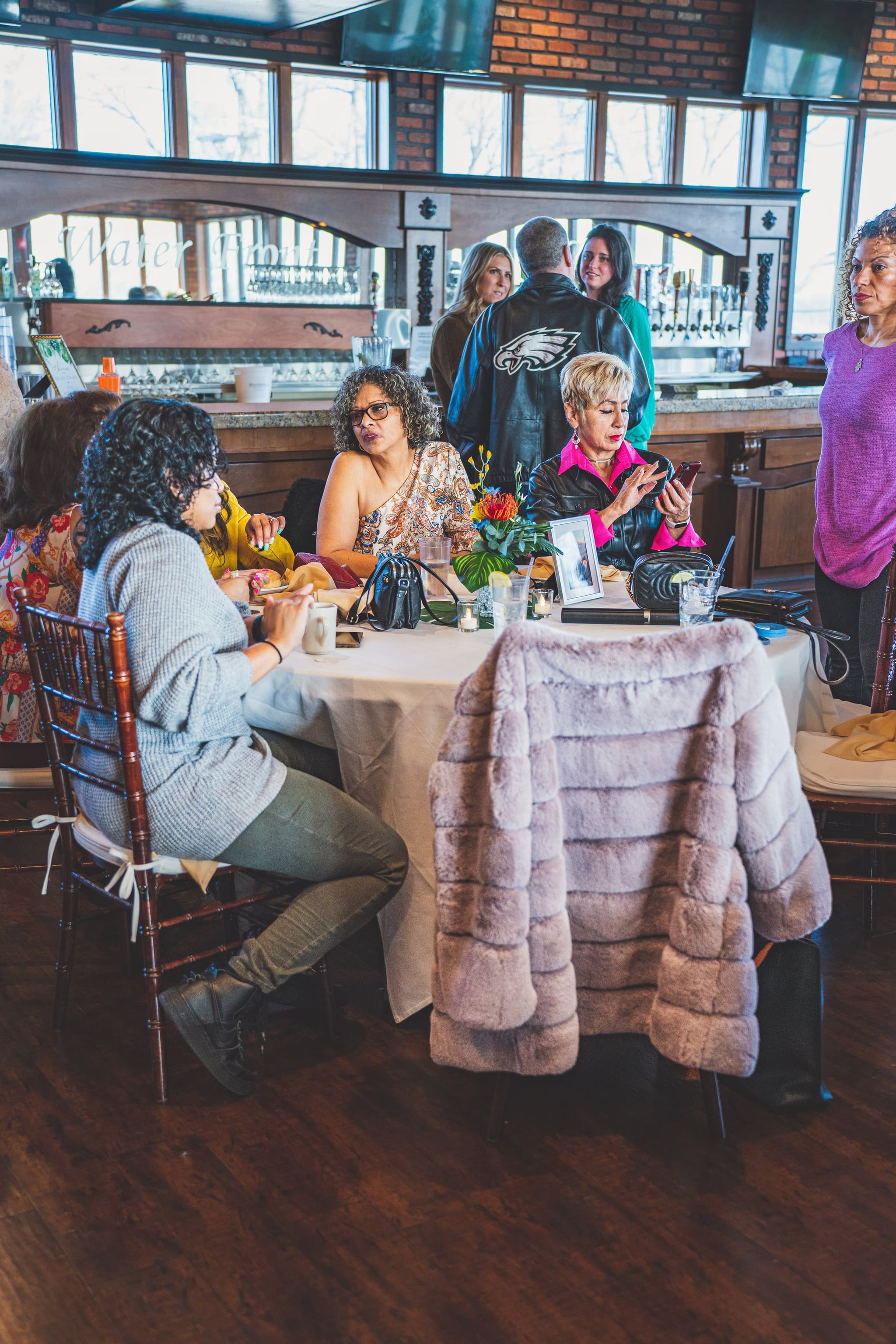 Guests mingling and conversing around a white-clothed table at the bridal shower venue