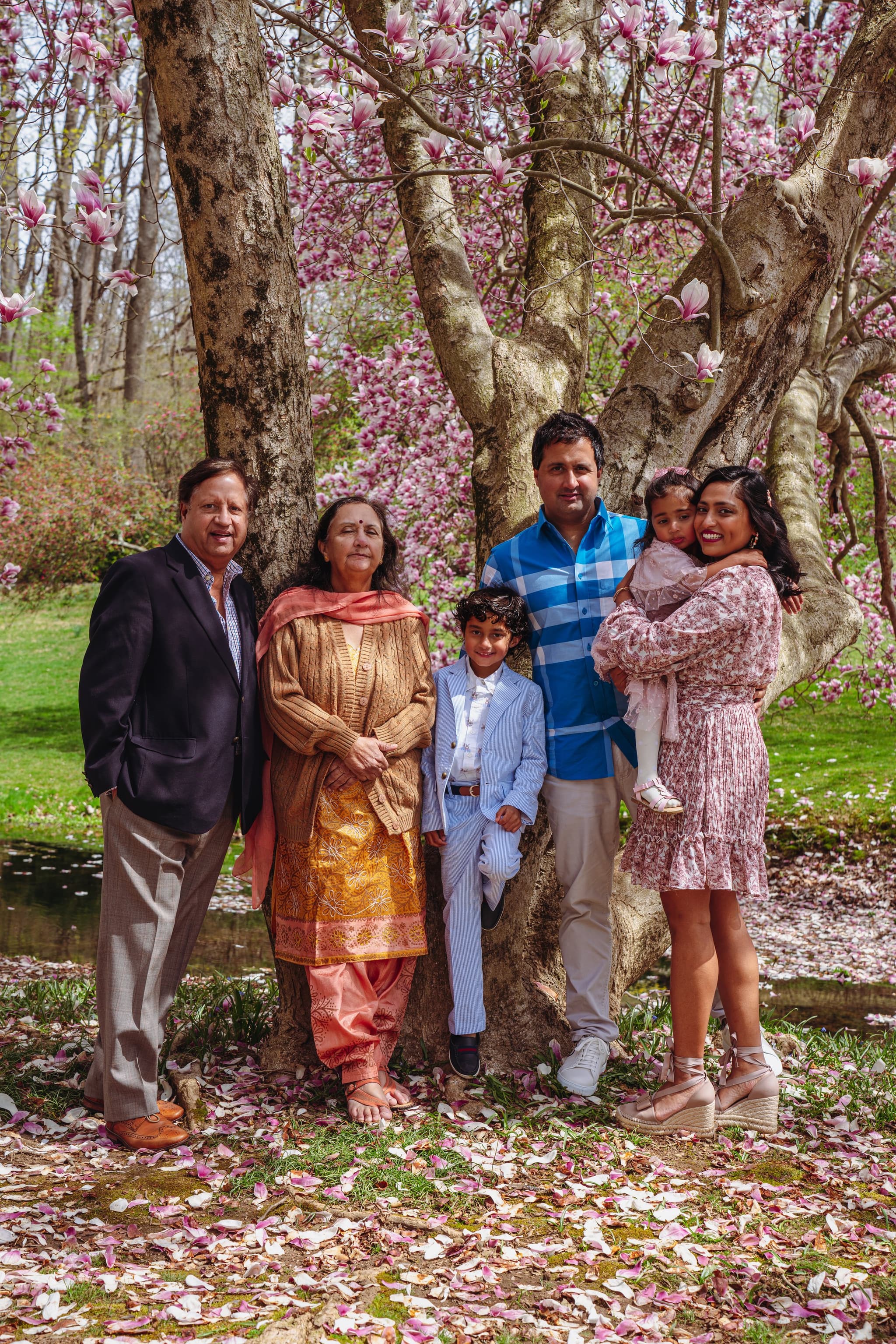 Multi-generational family portrait standing together under a blooming magnolia tree