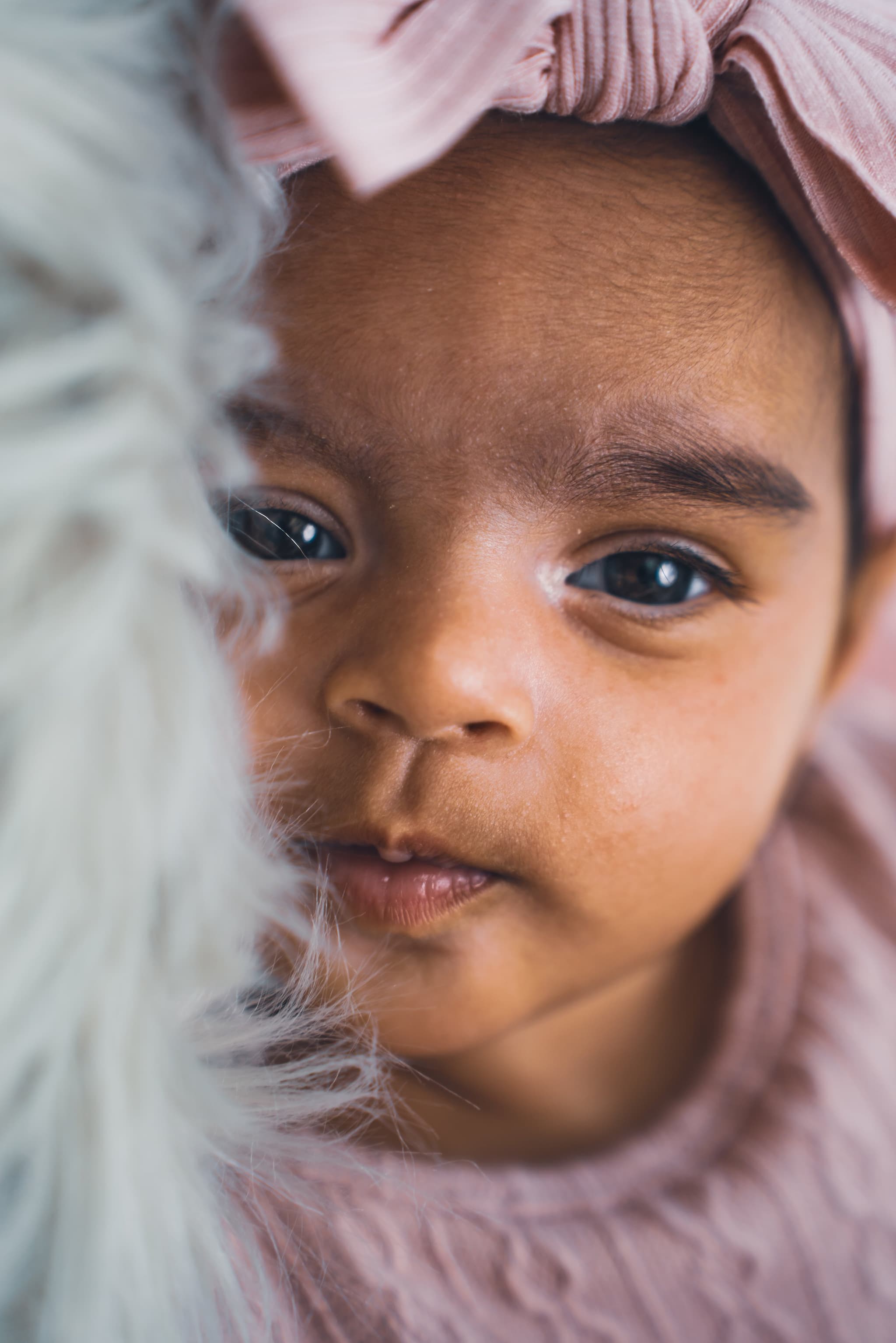 Close-up portrait of baby's face with pink bow headband