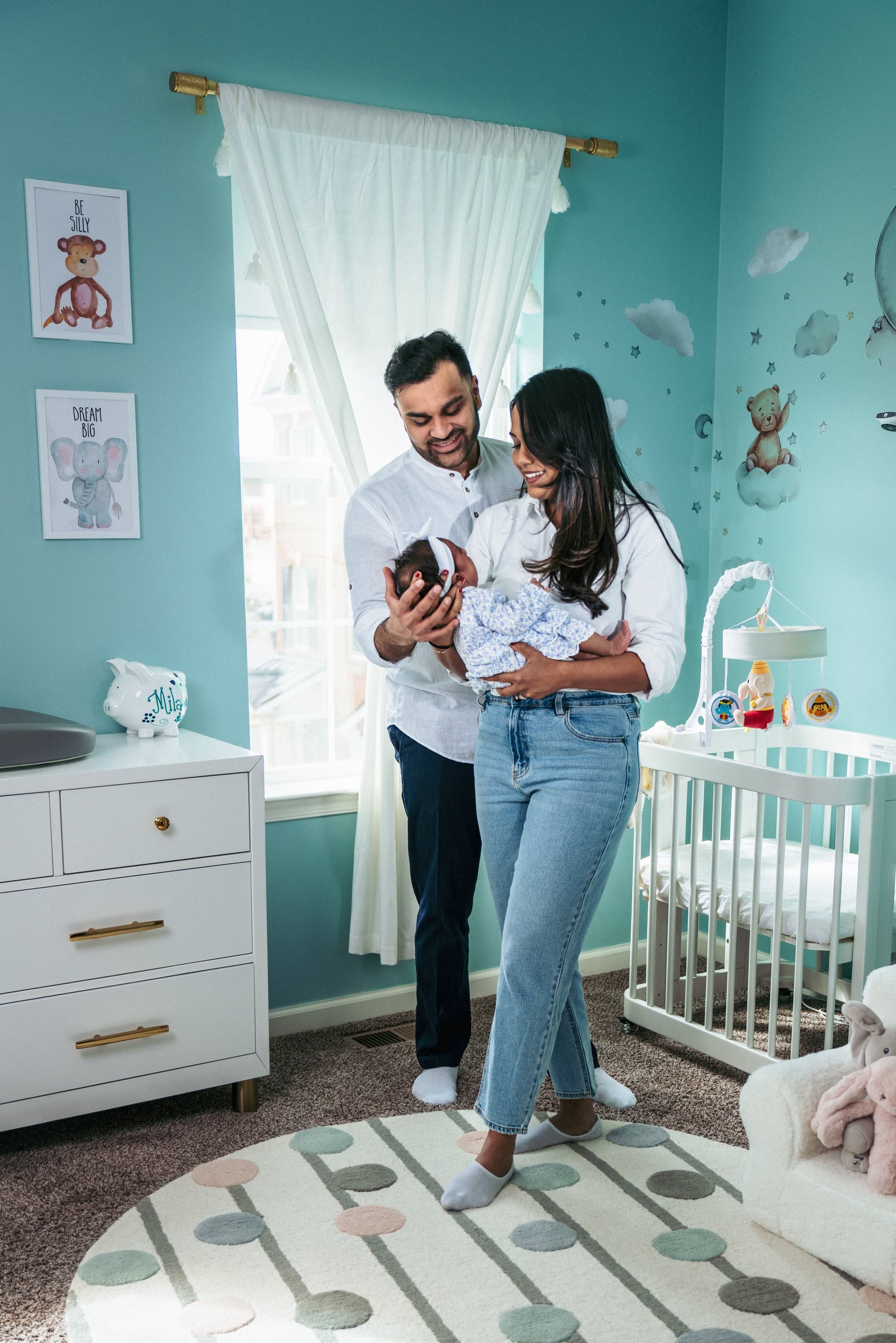 New parents standing together in the nursery, father cradling their newborn