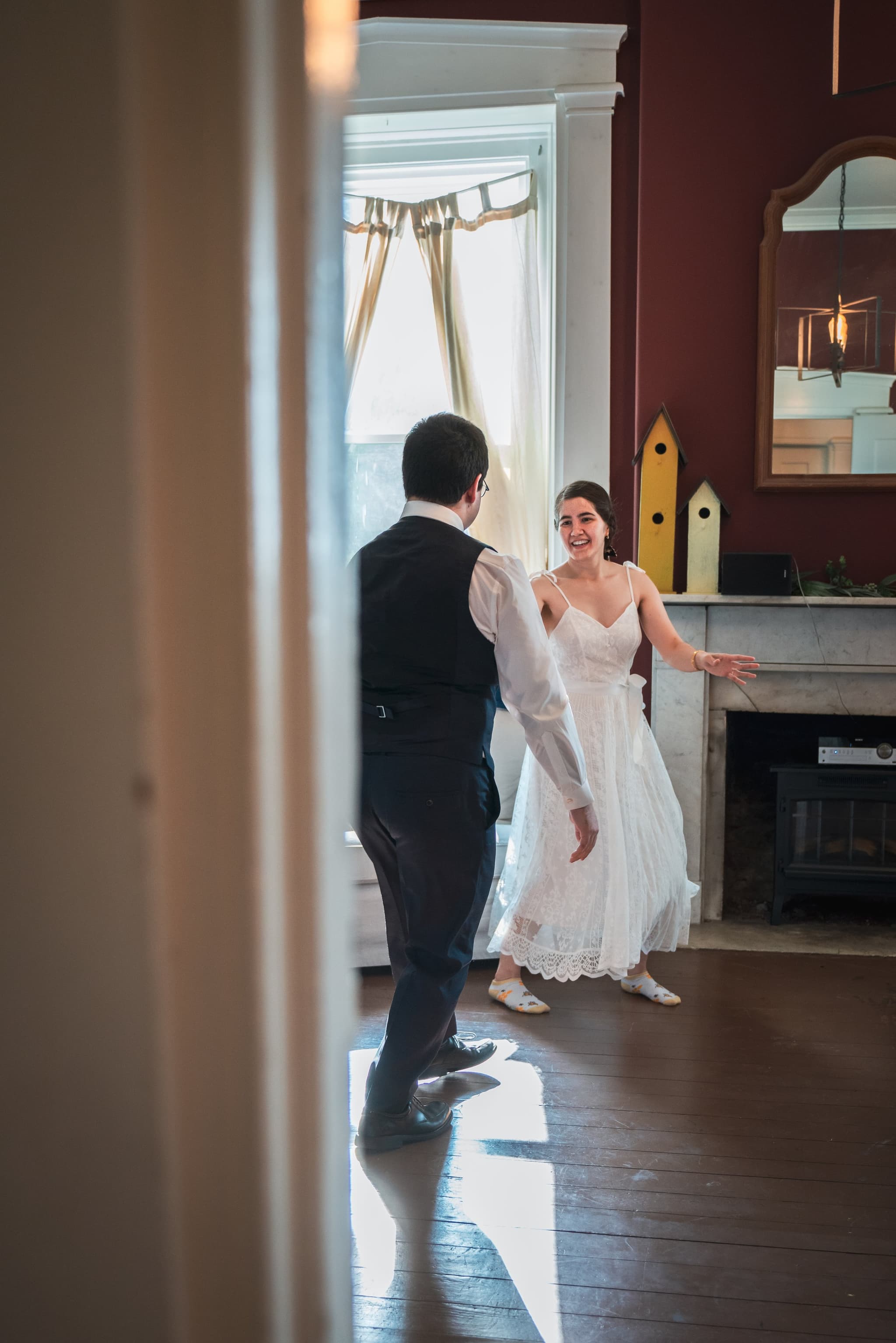 First look moment — bride spinning toward groom framed through a sunlit doorway