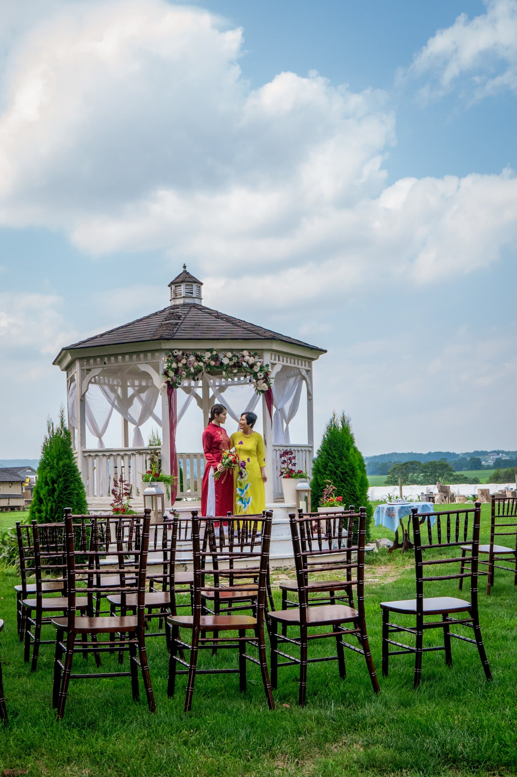 Outdoor wedding ceremony at a white gazebo with traditional Vietnamese attire
